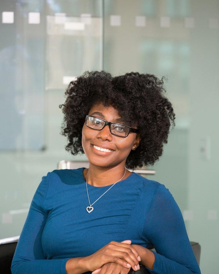 A woman in glasses and a blue top, smiling